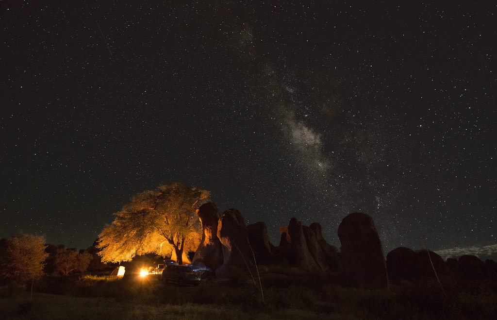 Campfire glow beside an SUV under the Milky Way