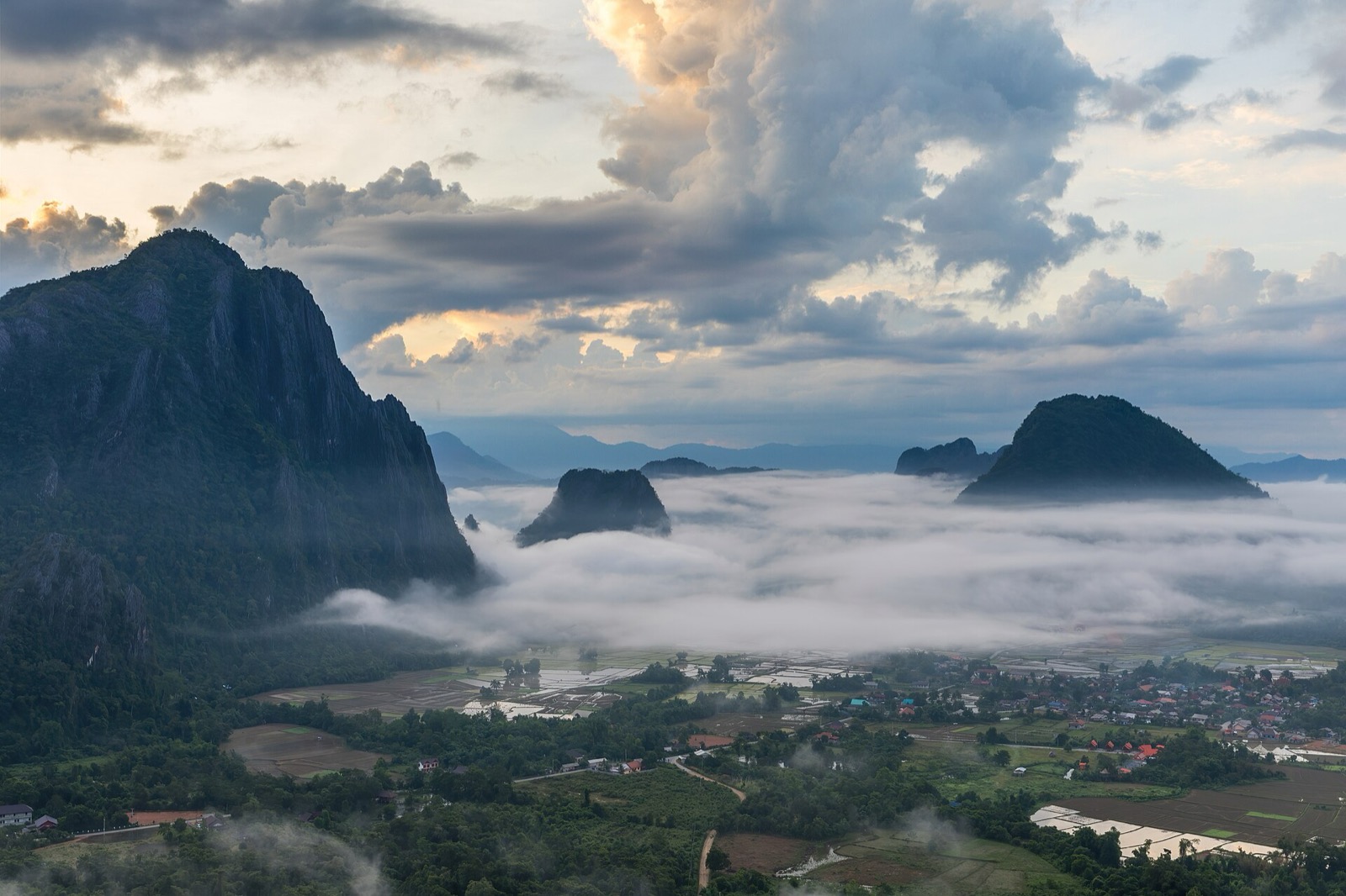 Sea of clouds around green peaks at sunrise