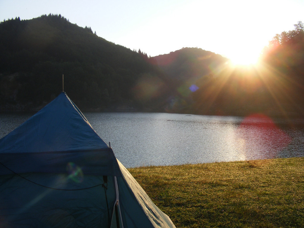 Morning sun over a calm lake beside a campsite